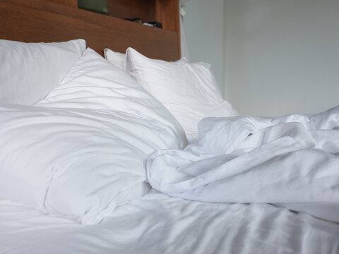 Comfortable Bed With White Pillows and Crumpled Sheets in Room