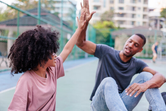 Friends high-five on a court, celebrating success together.