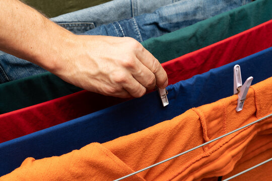 Hand clipping colorful clothes on drying rack