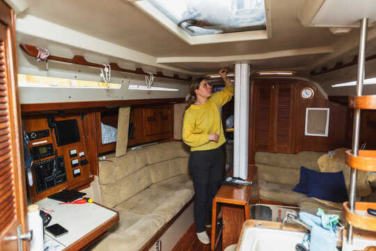 Woman Checking Ceiling Hatch and Interior Lighting on Sailing Boat