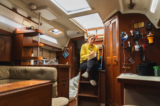Female sailor writing her personal travel diary in a sailboat cabin