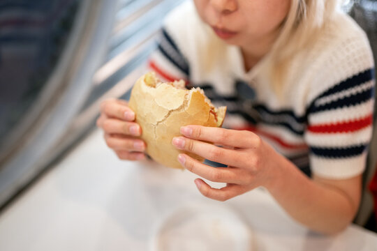 Woman eating fast food burger during lunch break