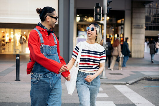 Happy couple holding hands walking on city street