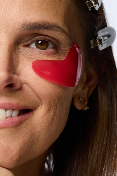 Person Applying Red Gel Patch on Face While Smiling