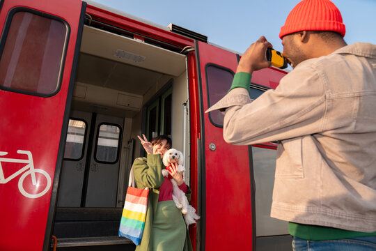 Couple Take Pictures at a Train Station With a Small Dog