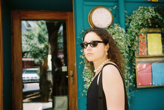 Sunlit Woman Outside Turquoise Shop on 35mm Film