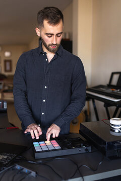 Dj using pad controller with colorful lights in home studio