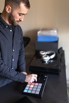 Dj using pad controller with colorful lights in home studio