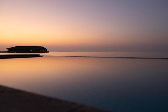 Maldives infinity pool villa at sunset warm reflections