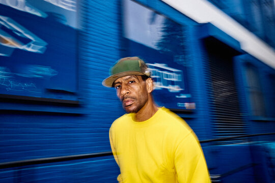 Man moves quickly beside a blue wall in Brooklyn