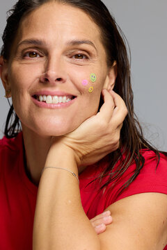 Smiling Woman Poses With Stickers on Her Cheek in Simple Outfit