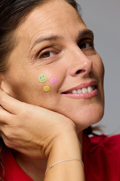 Woman Smiles With Stickers on Her Face in Simple Setting