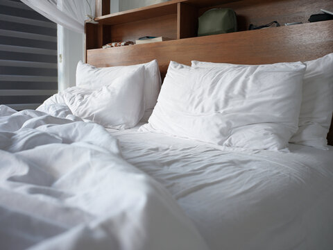 Comfortable Unmade Bed With White Sheets and Pillows in a Bedroom