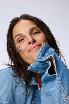 Woman With Blue Stars on Face Smiles While Wearing Denim Jacket
