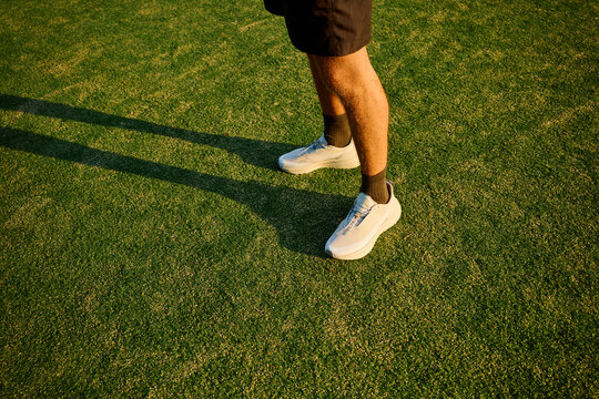 Person Standing on Green Grass Wearing Sports Shoes