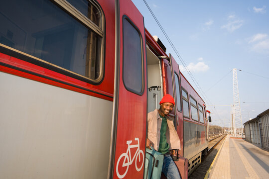 Smiling Man Step Off Train Holding His Luggage 