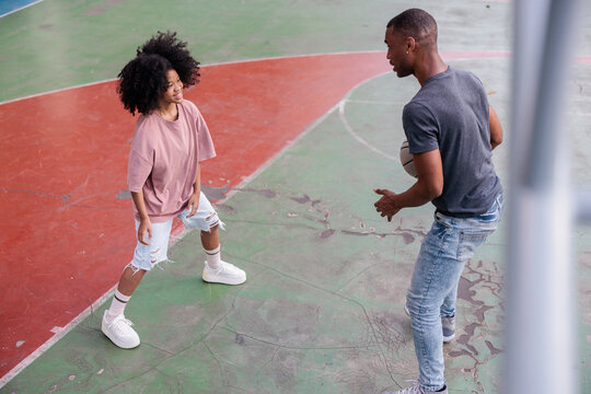 Two people playing basketball on an outdoor court.
