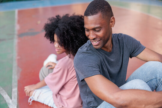 Father and daughter sitting back-to-back on a basketball court