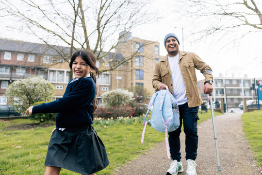 Smiling parent with disability and daughter walking home from school