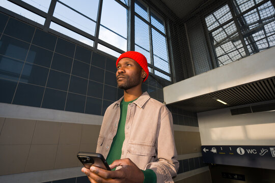 Man Stands in Building While Using Smartphone 