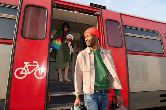 Two People and a Dog Arrive at a Train Station