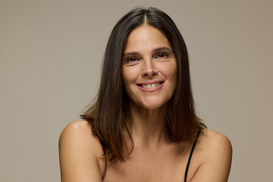 Woman Smiles While Posing Against a Simple Background