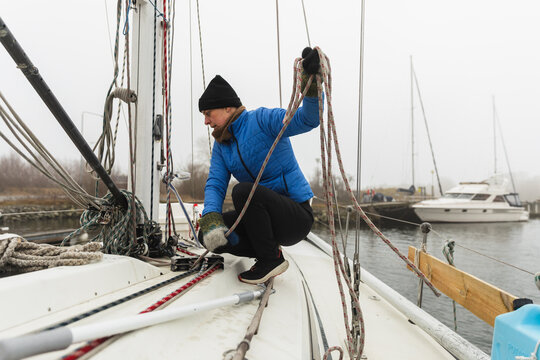 Woman Sailor Organizing Ropes and Rigging on Sailboat Deck