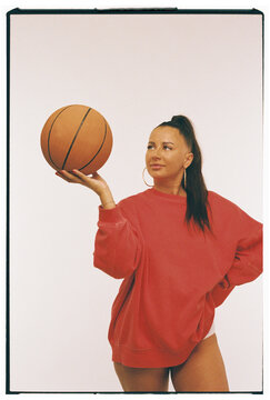 Woman Balancing Basketball on Hand in Studio Portrait