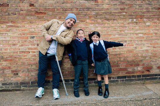 Father with crutch smiling picking up children from school
