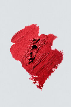 Swatch of textured red lipstick on plain white background.