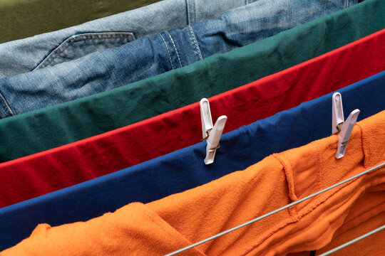 Colorful clothes hanging on drying rack with clothespins indoors