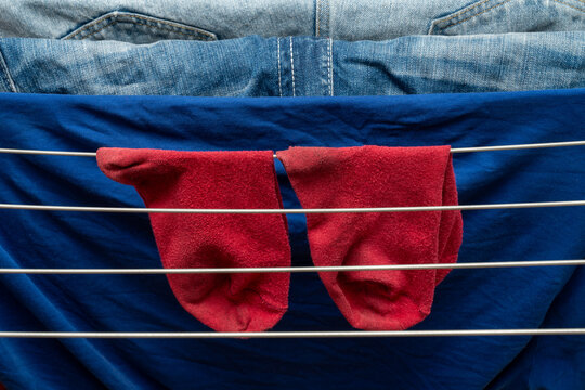 Red socks drying on rack over blue fabric and denim background
