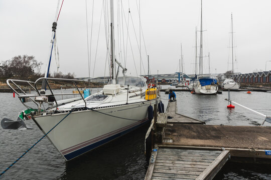 Woman Sailor Mooring Sailboat to Wooden Dock in Marina