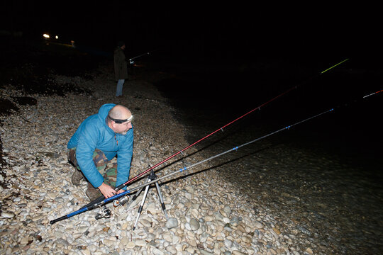 Angler sets up his fishing rods on the shore