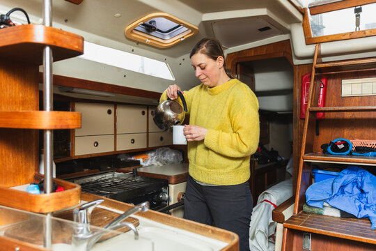 Woman Making Tea in a Sailing Boat Galley Kitchen