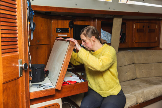 Woman Sailor Organizing Equipment at Sailing Boat Chart Table