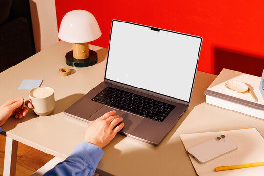 Hand using laptop mockup in modern red office with coffee