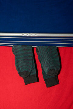 Dark striped socks drying on rack against red and blue fabric
