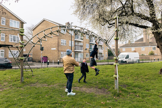 Father and children playing on monkey bars outdoors