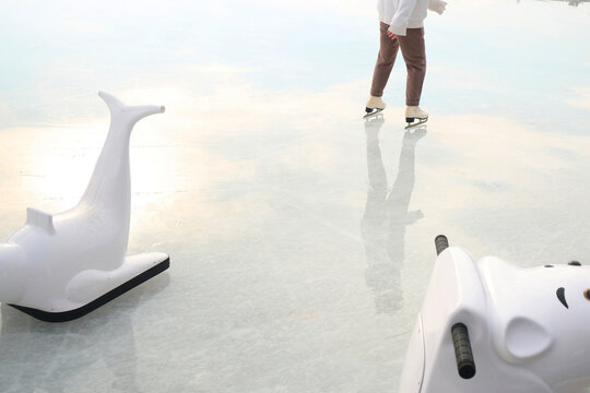 Beginner on a skate rink close to assistants