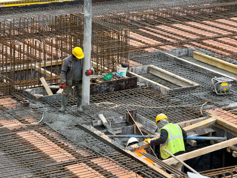 Construction Workers Pouring Concrete and Rebar Preparation at Site