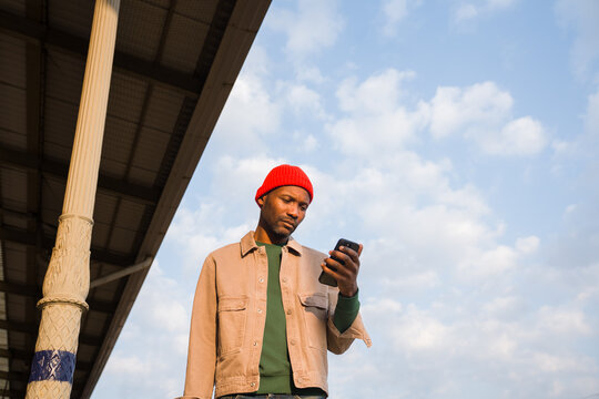 Man Checks Phone Under Blue Sky