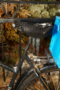 A black bicycle is coated in glistening ice and icicles