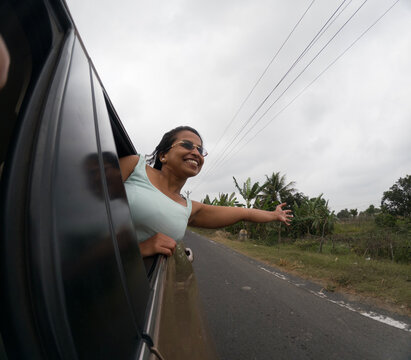 Indian woman travelling in a car and stretching arms
