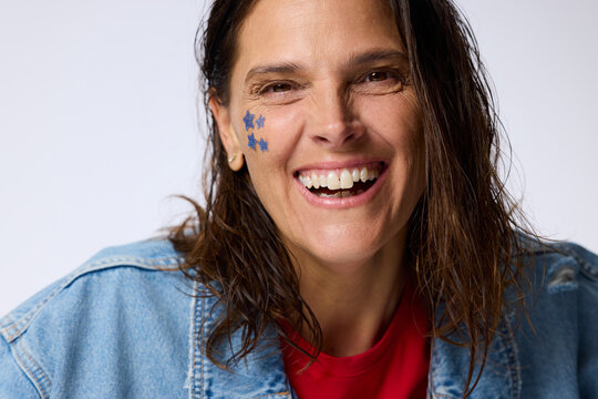 Woman Smiles With Blue Star Face Paint on Her Cheek Indoors