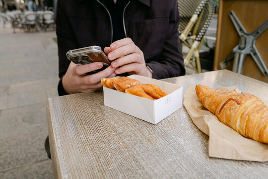 young man sitting in caf&eacute;,  croissant and bugne in Lyon France
