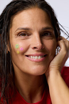 A Woman With Wet Hair is Smiling and Resting Her Chin on Her Hand