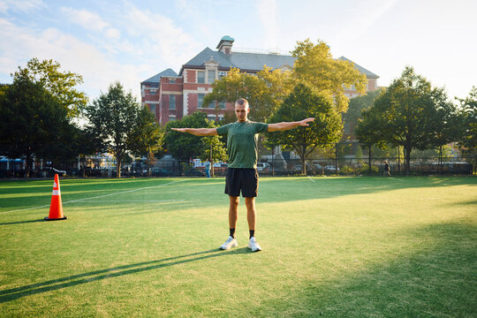 Man Stretches Arms on a Sports Field in the Morning