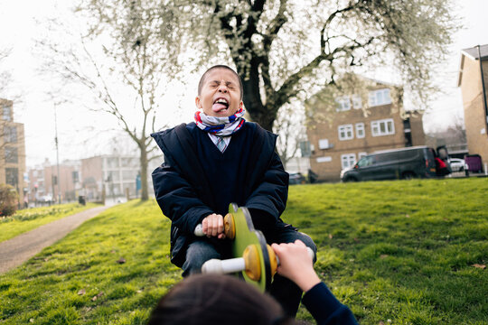 Playful boy making funny face on playground seesaw