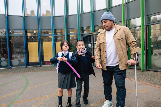 Father with crutch picking up children from school